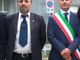 Due persone in piedi, una con fascia tricolore