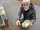 Uomo seduto vicino a una panchina danneggiata