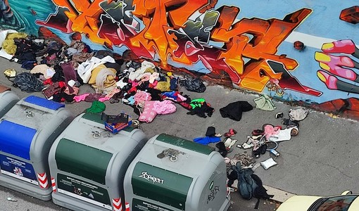 Marciapiede sommerso dai rifiuti e dai vestiti in Barriera
