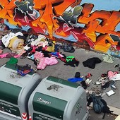 Marciapiede sommerso dai rifiuti e dai vestiti in Barriera