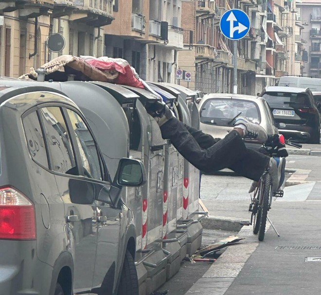 Un uomo in equilibrio dentro il bidone dei rifiuti