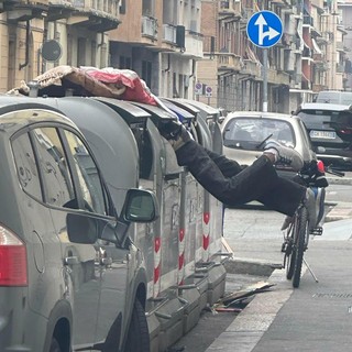 Un uomo in equilibrio dentro il bidone dei rifiuti