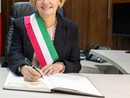 Donna sindaco con fascia tricolore che firma documenti