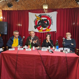 tavolata di relatori contro la caccia con persone sedute davanti a cartelli e insegne