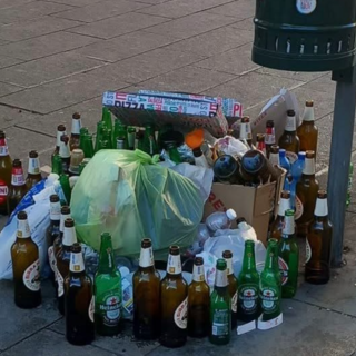 Bottiglie vuote e cartoni della pizza abbandonati vicino a un cestino dei rifiuti Bottiglie vuote e cartoni della pizza abbandonati vicino a un cestino dei rifiuti