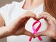 donna fa con la mani il simbolo della lotta al cancro al seno